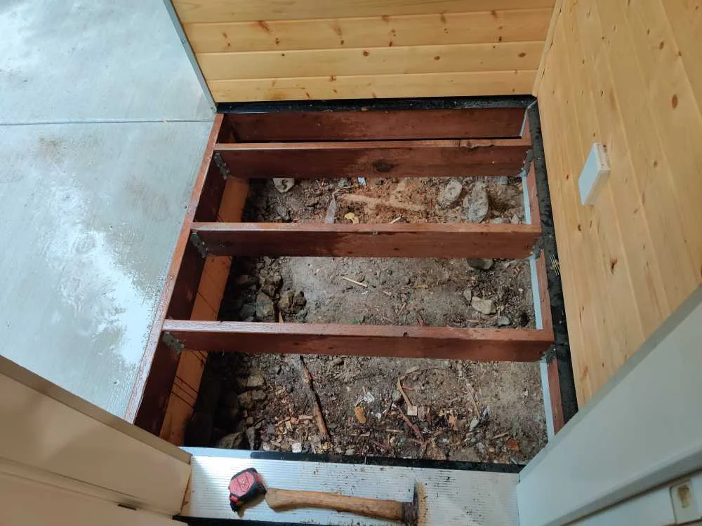 Exposed wood framing for a small front-door deck at the second house