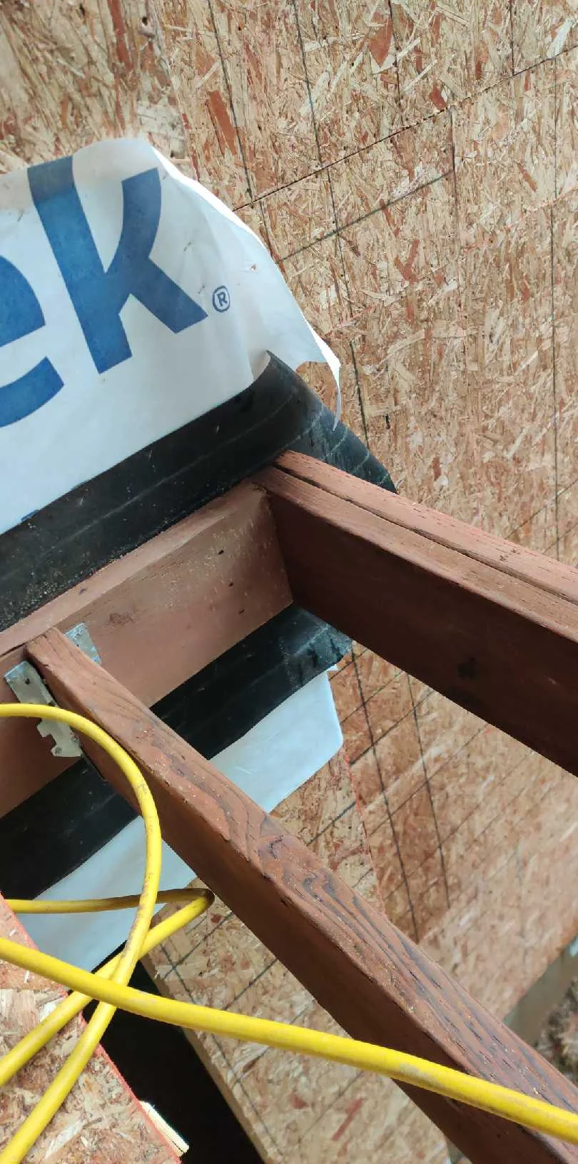 Close-up of second-floor deck framing and weatherproofing at the house connection