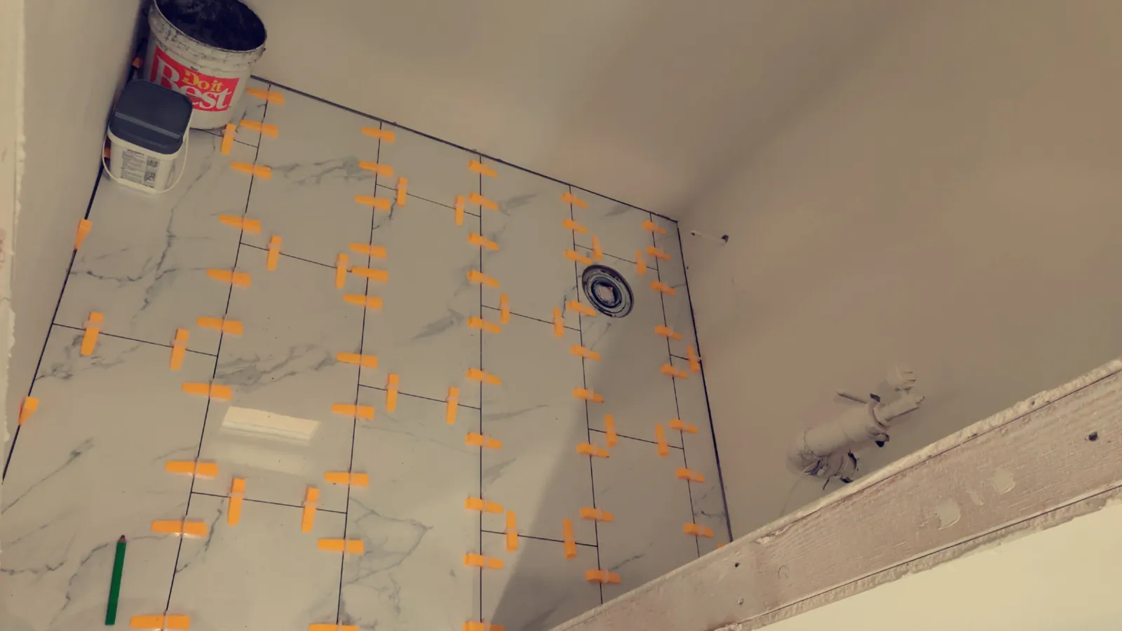 Floor tile being installed over waterproof uncoupling membrane in a bathroom